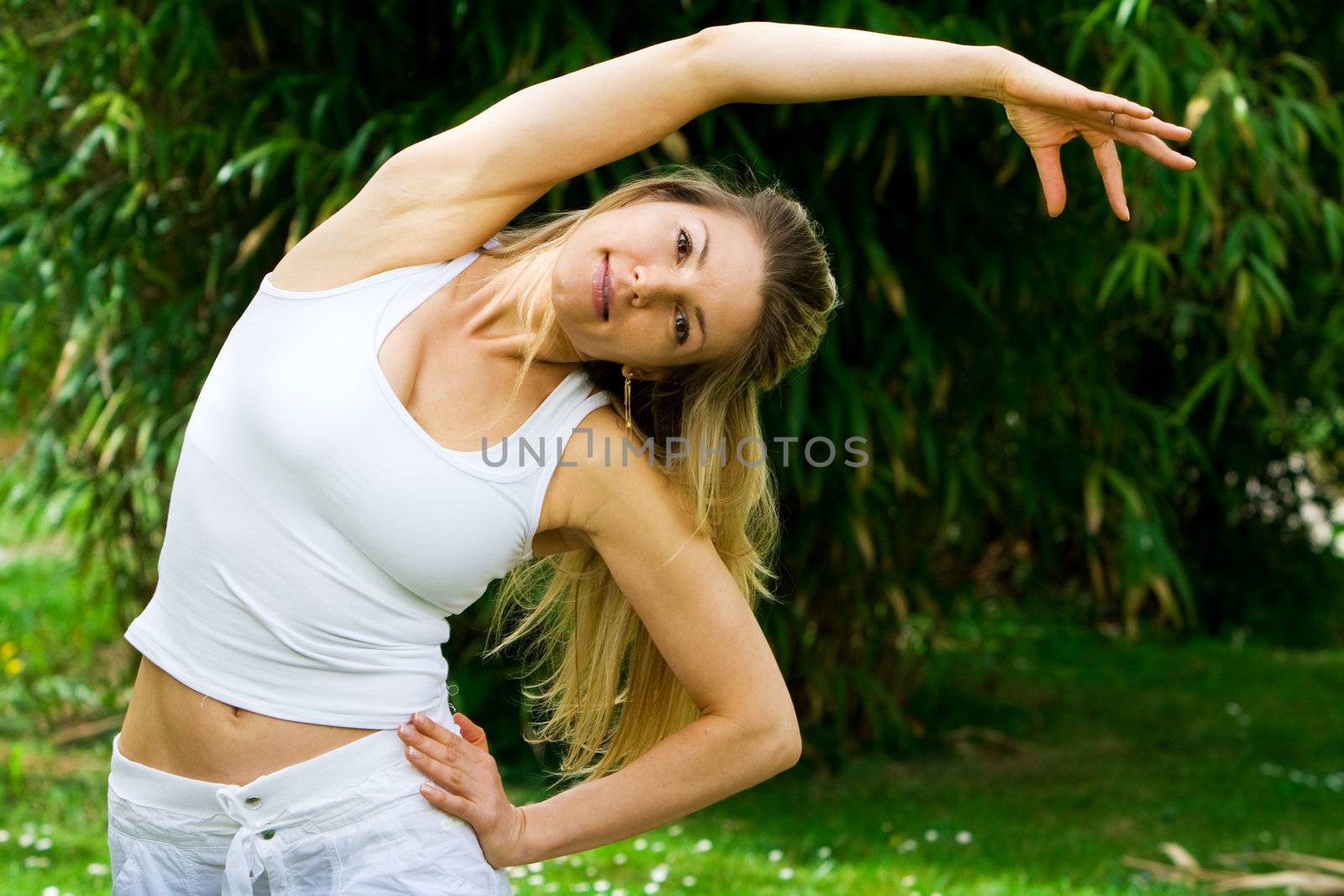 Blonde girl in nature green park exercising yoga, fitness program