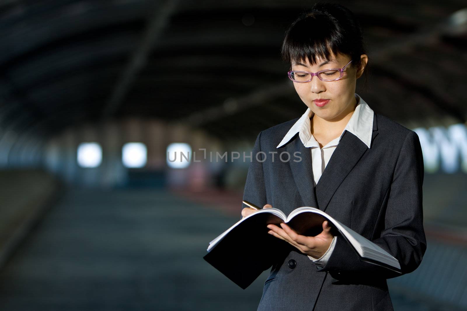 Young asian business woman standing holding journal or report