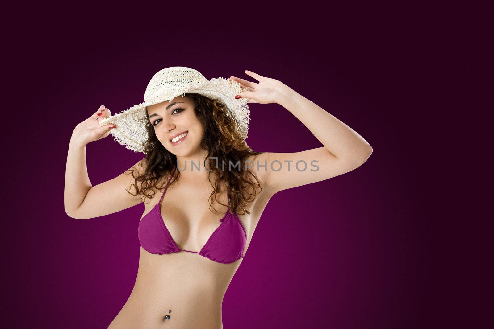 Portrait of a beautiful young woman in bikini posing on a violet background