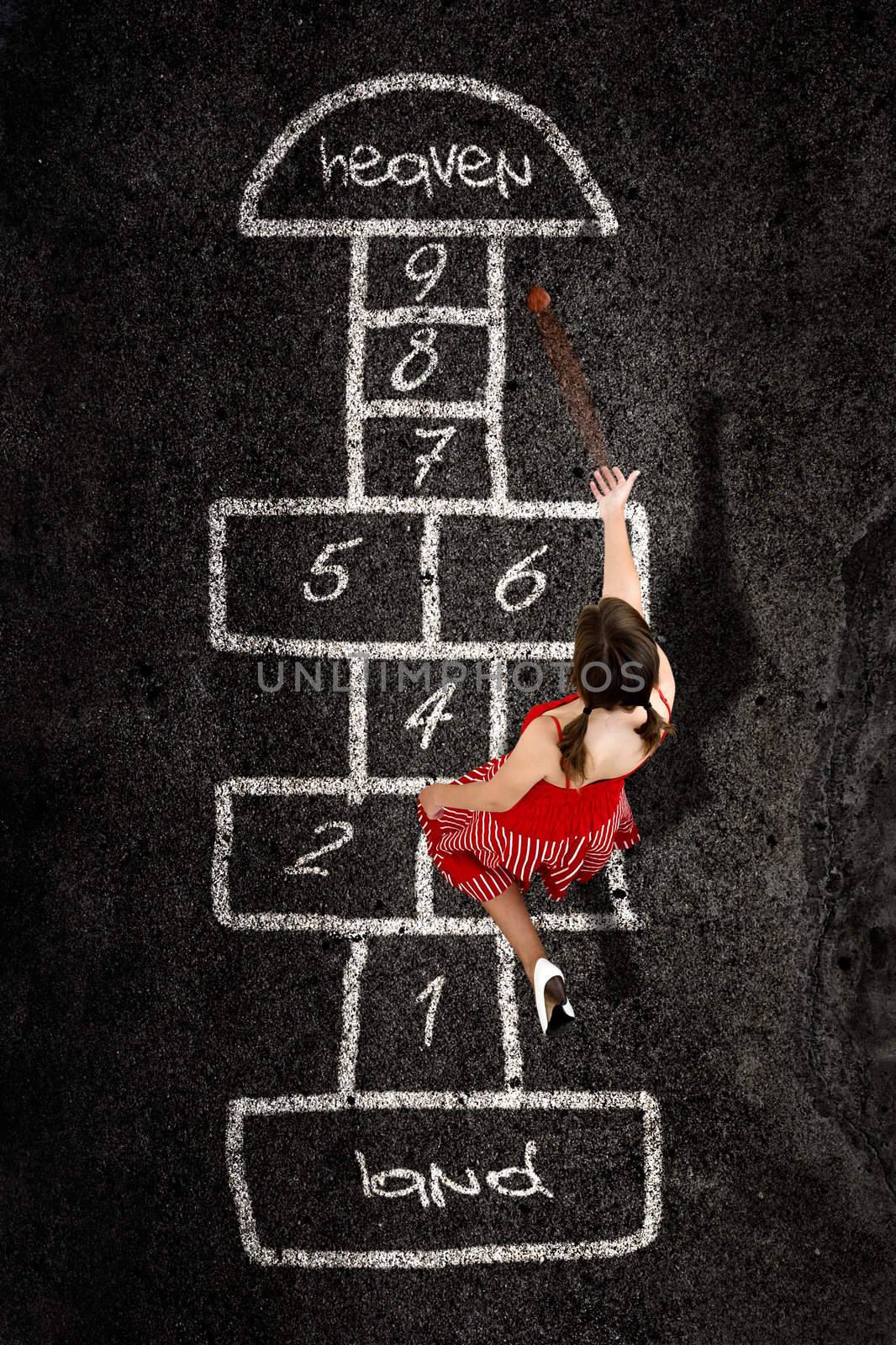 Beautiful young woman playing hopscotch with a red dress 	
