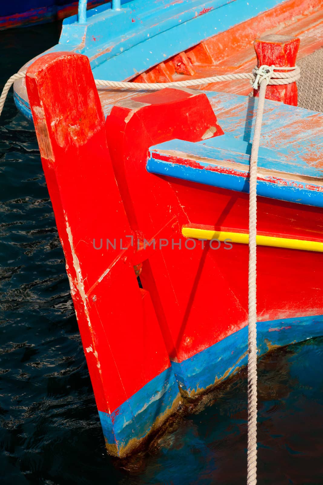 Stern and rudder of small old greek fishing boat moored in harbor.