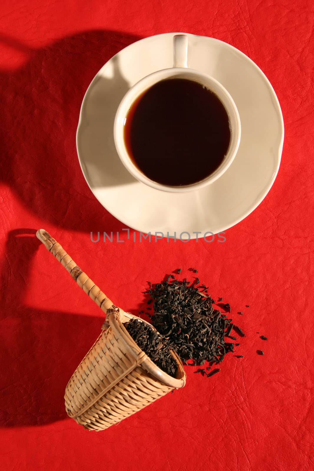 A wicker scoop with herb tea leaves and a cup of tea by Erdosain