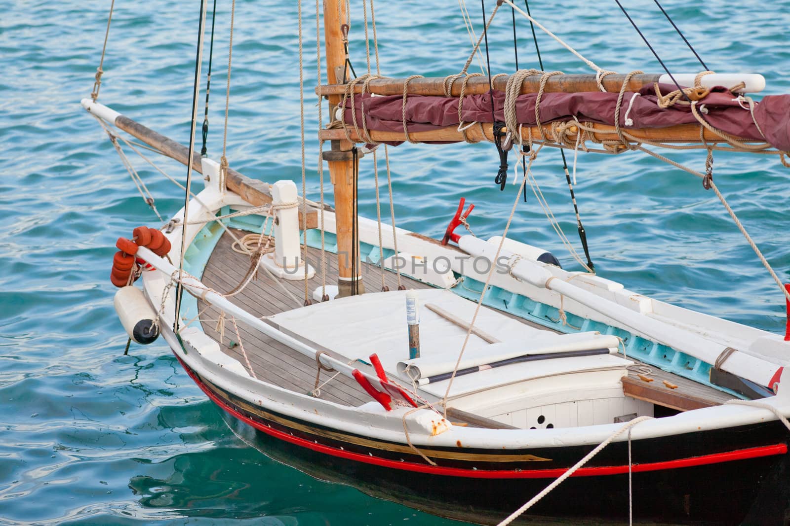 Small traditional Greek sailboat moored in harbor.