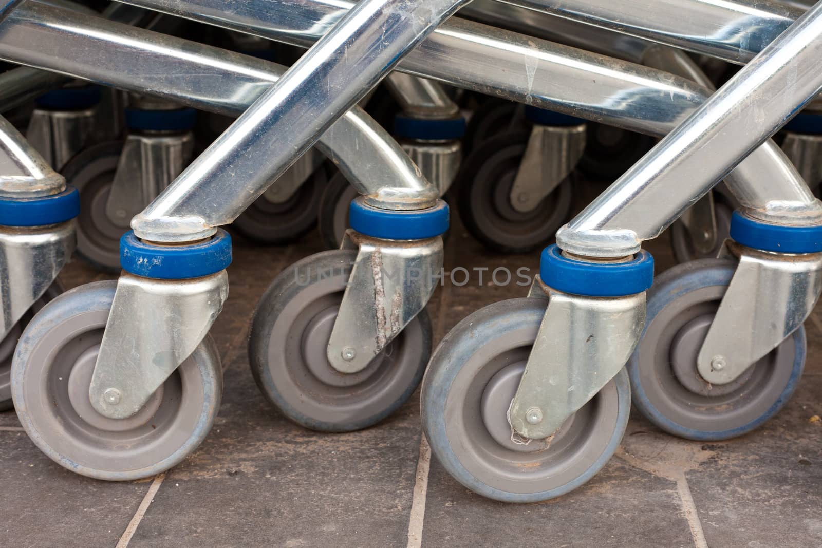 Wheels of shiny metal shopping carts stacked in a row.