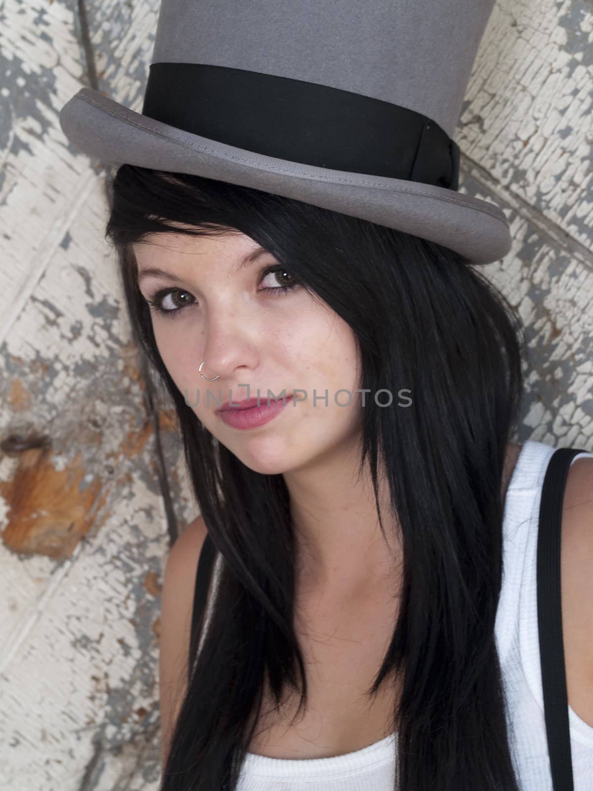 Teen girl in a top hat on a rustic background