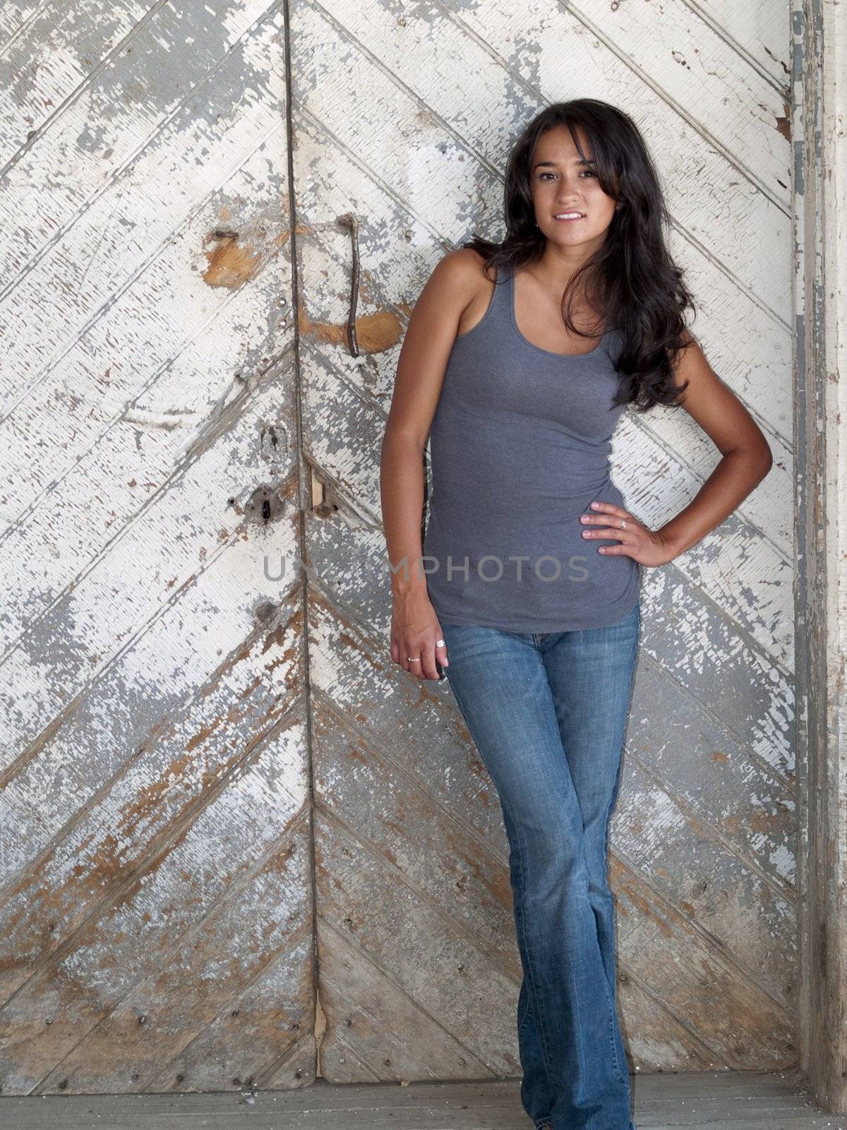 Young, native american woman standing in front of a barn door