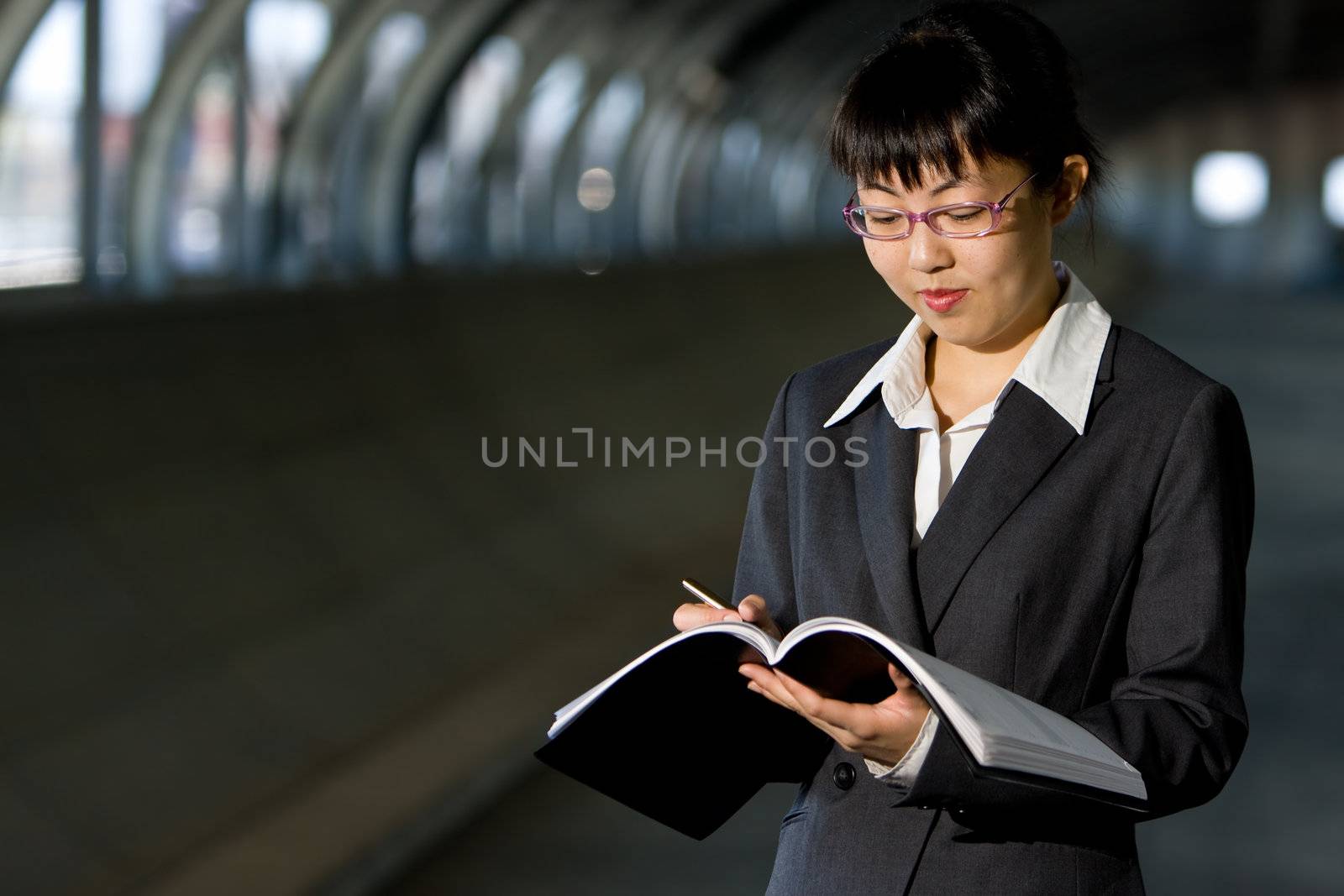 Young asian business woman standing holding journal or report