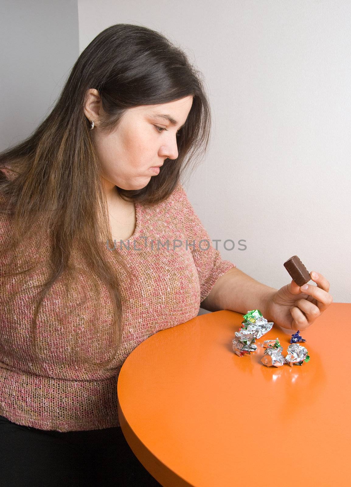 Stout woman contemplating over wrappers of sweets