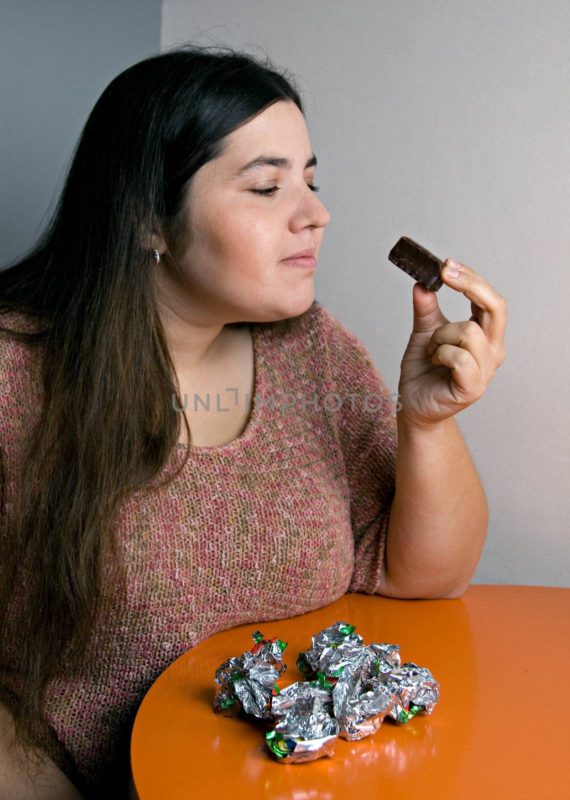 Stout woman contemplating over wrappers of sweets