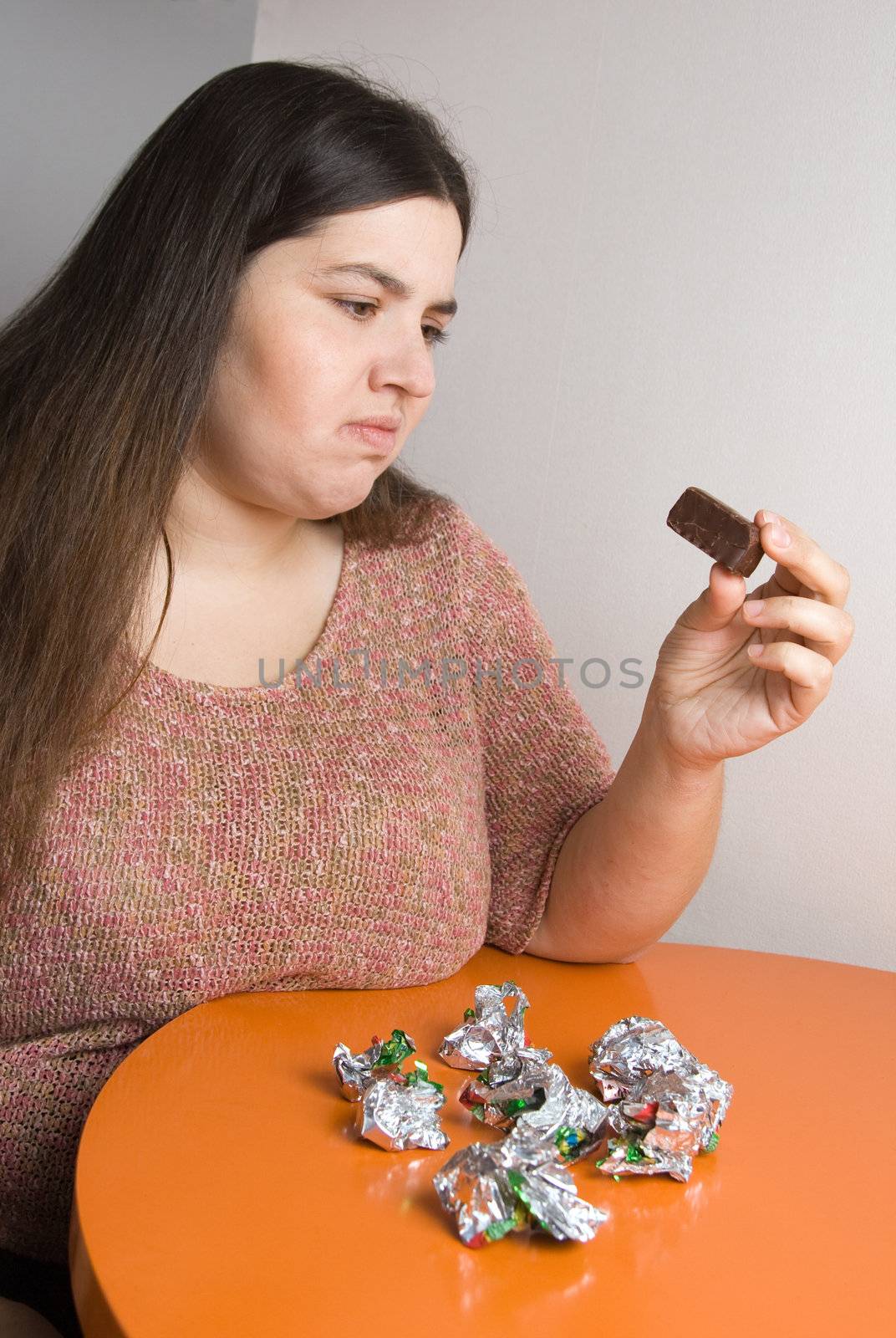 Stout woman contemplating over wrappers of sweets