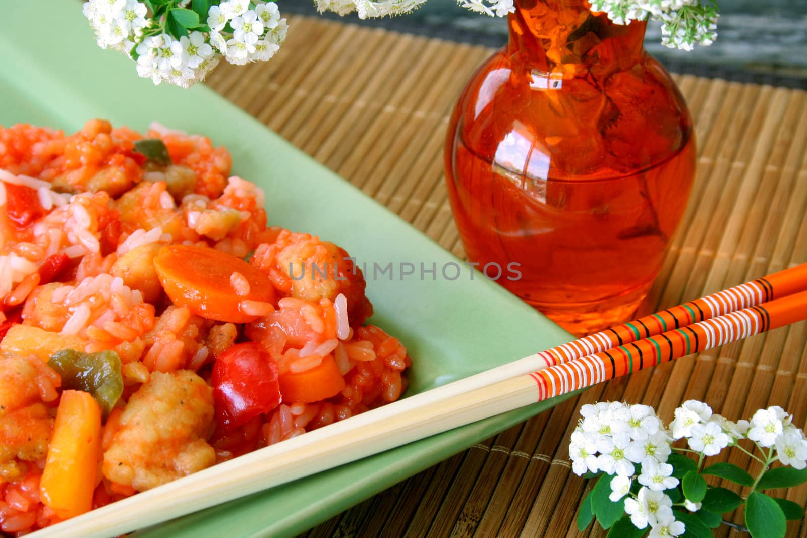 Sweet and Sour Chicken with chop sticks and fresh flowers on the side.