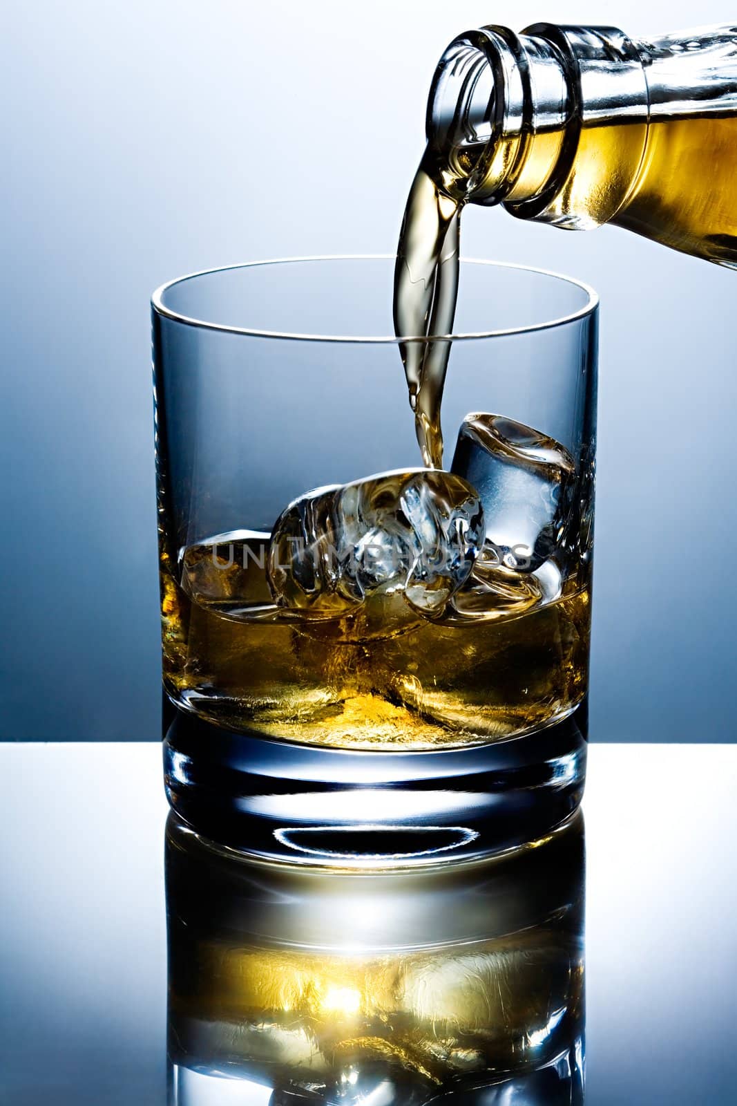 Filling of a glass of whisky with ice
