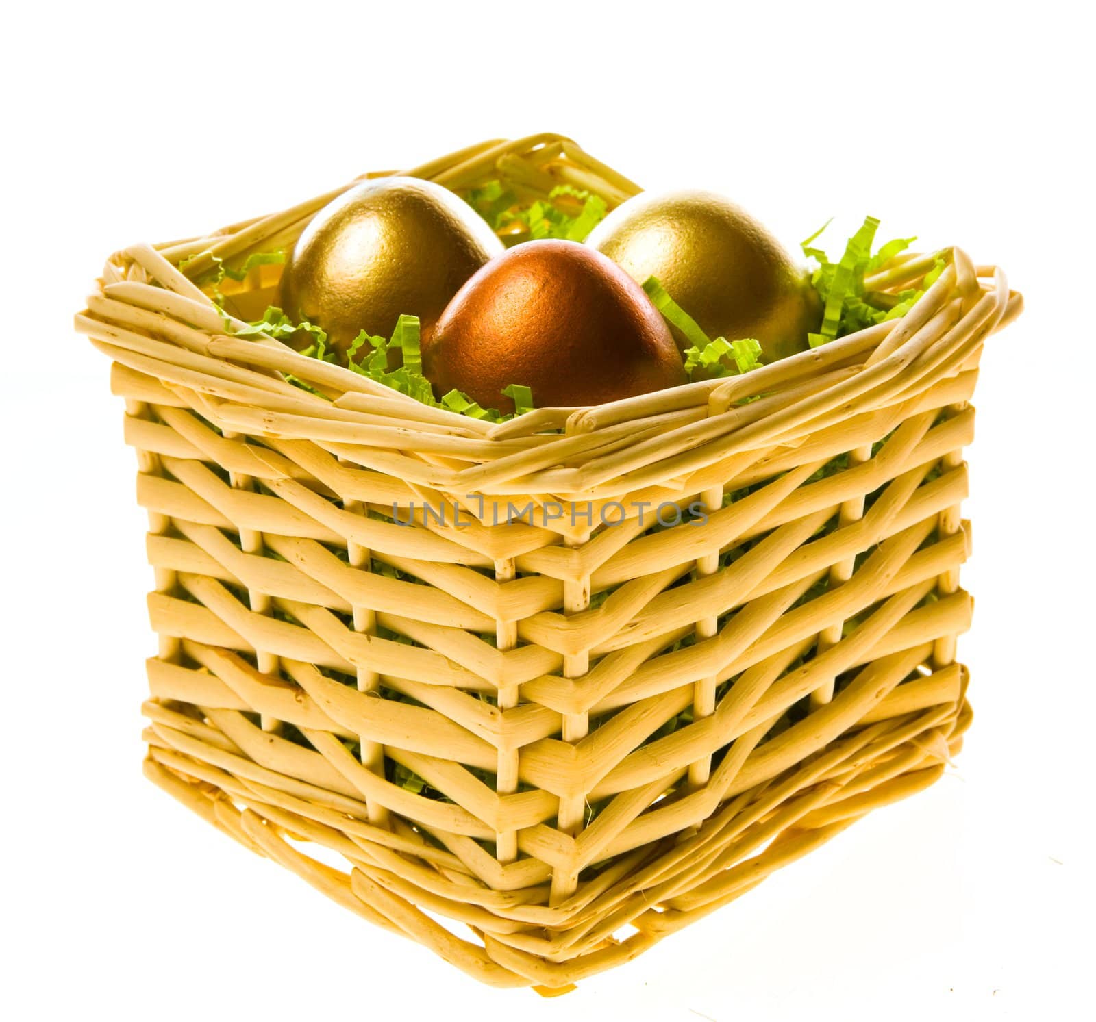 Three eggs, two gold and one bronze in a small basket on a white background
