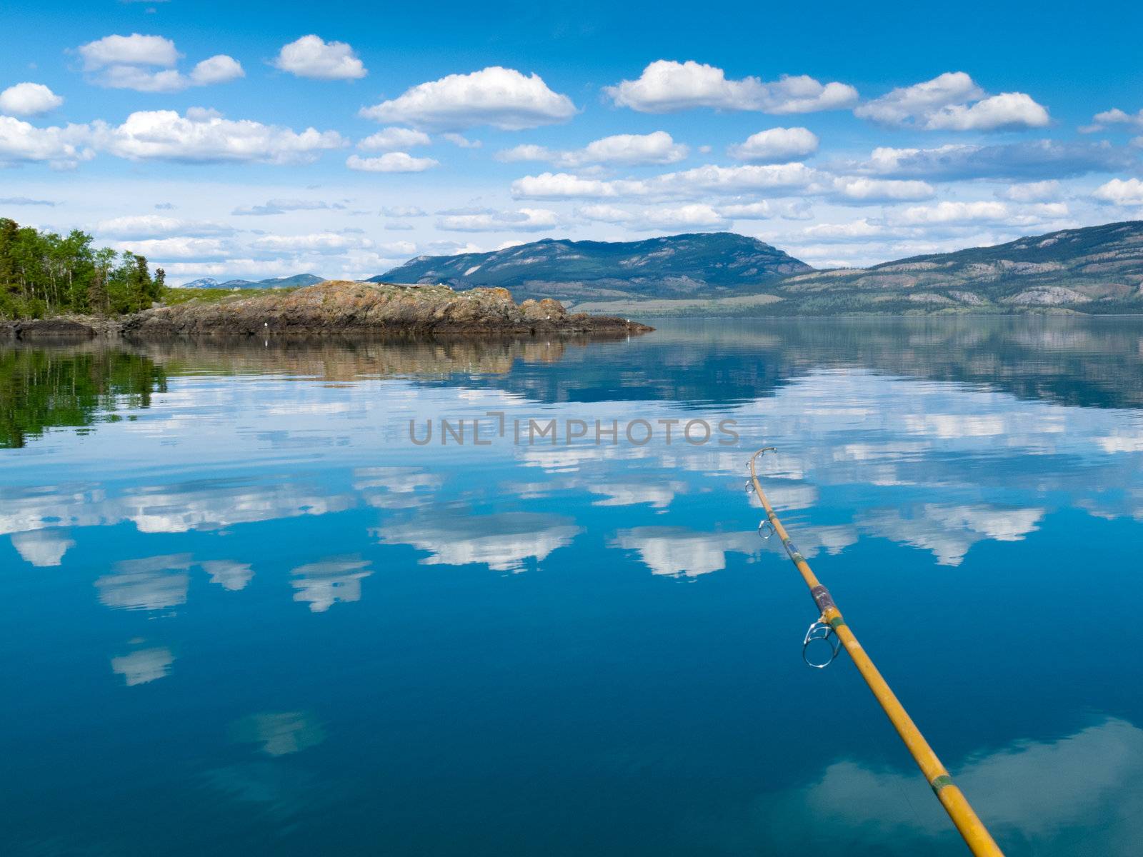 Fishing rod bends under weight of fish that just took lure in Lake Laberge, Yukon Territory, Canada