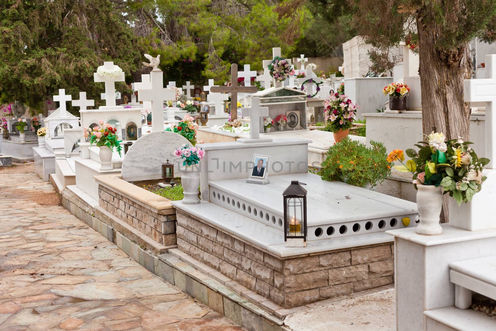 Typical Greek-orthodox cemetery in Greece, Europe, with flowers and images of loved ones (blurred) on graves.
