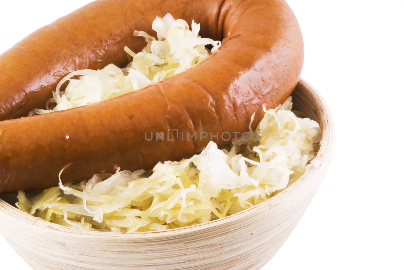 Close up of a wooden bowl with sauerkraut and a smoked sausage.
