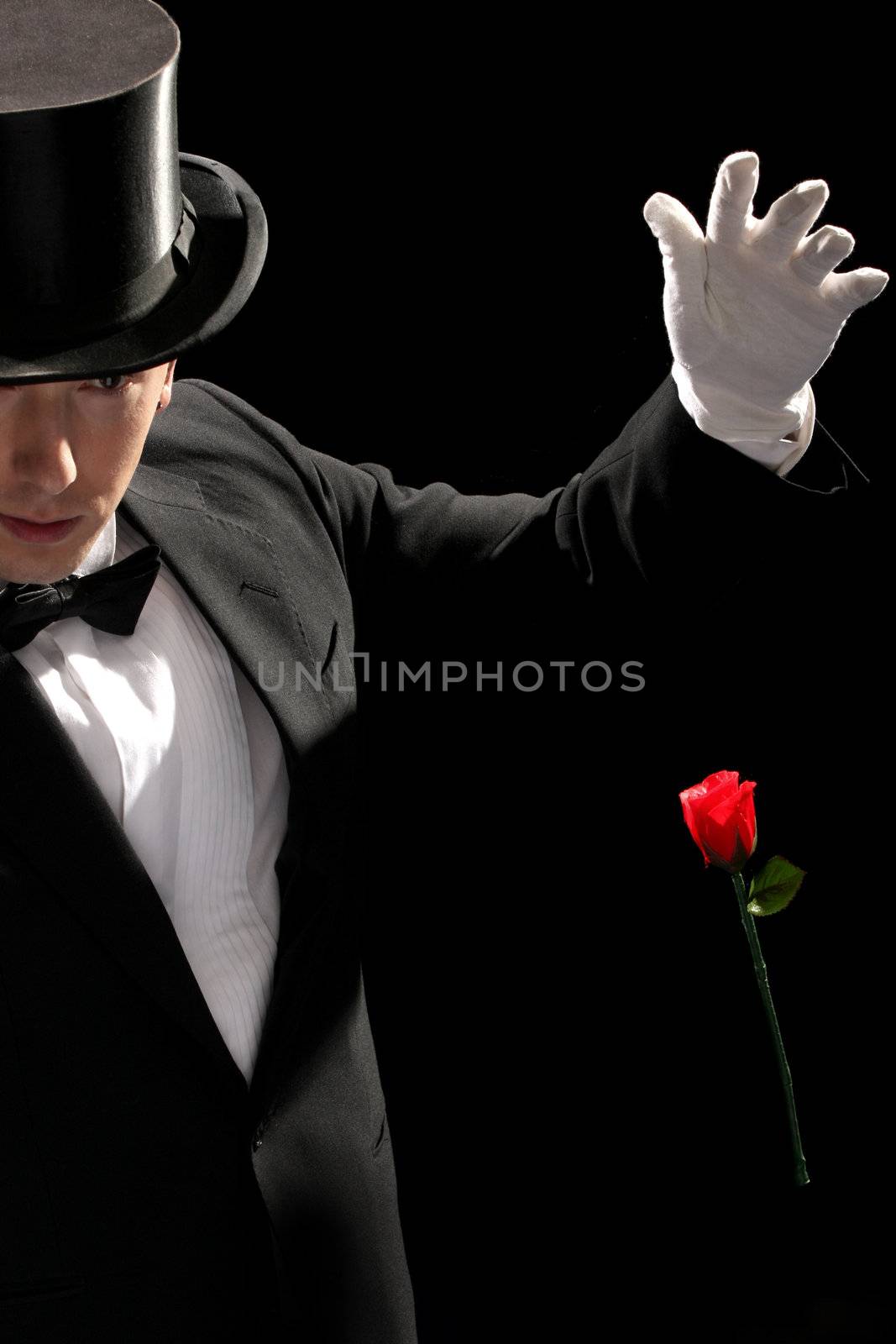 young magician performing red rose on black background