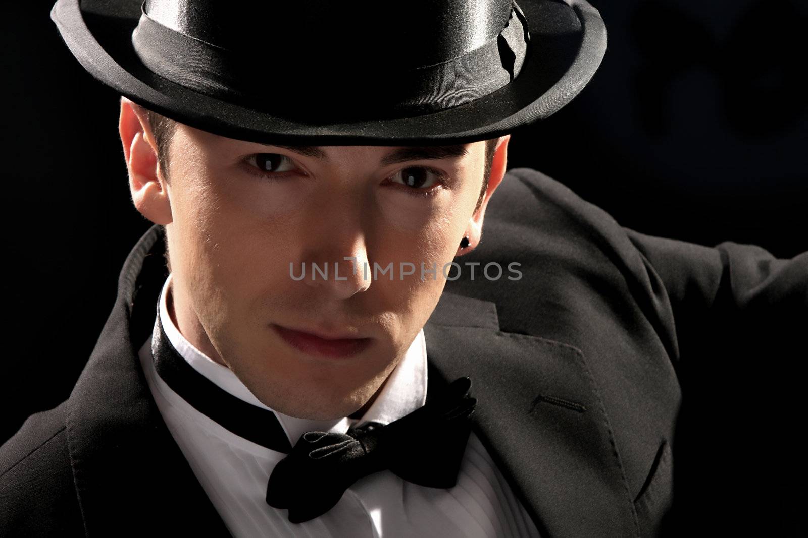 young magician with high hat on black background