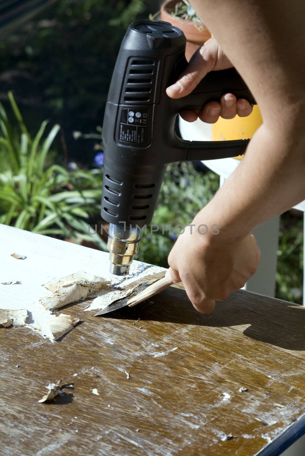 portrait of renovation; removing old paint using scraper and heat gun