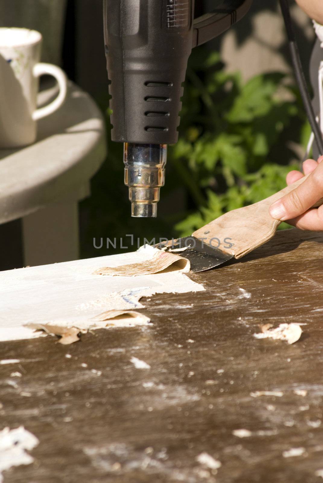 portrait of renovation; removing old paint using scraper and heat gun