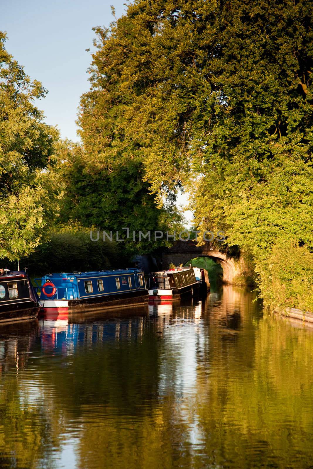 Vertical format of canal barges on river reflected in the calm water