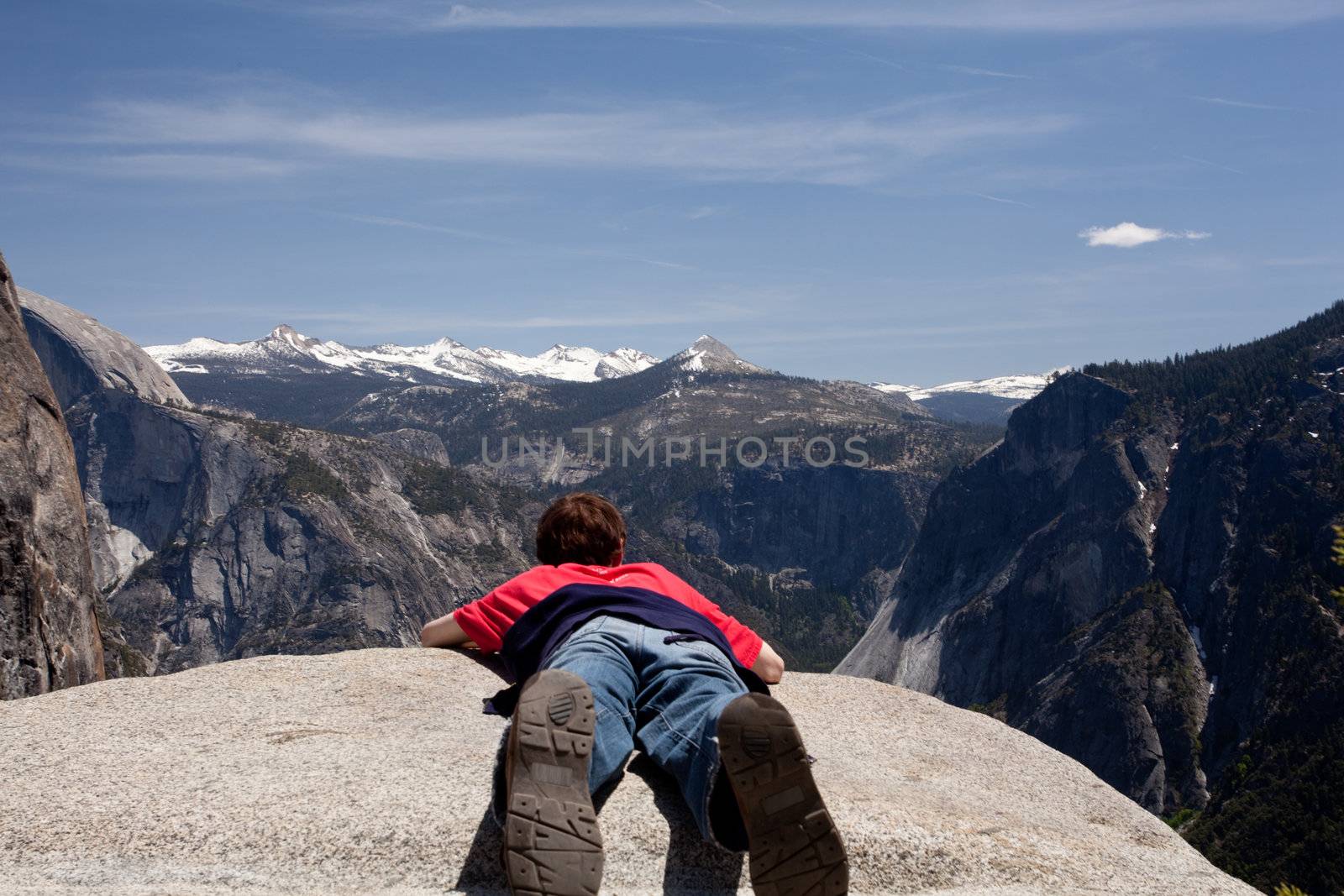 Young hiker lying prone over Yosemite by steheap