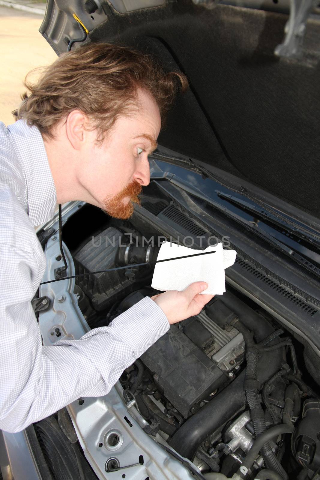 Funny man checking engine oil dipstick in car