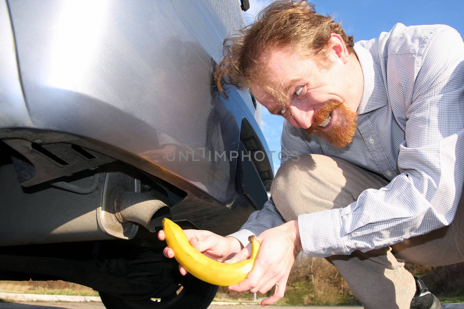 Man putting banana into car exhaust by vladacanon