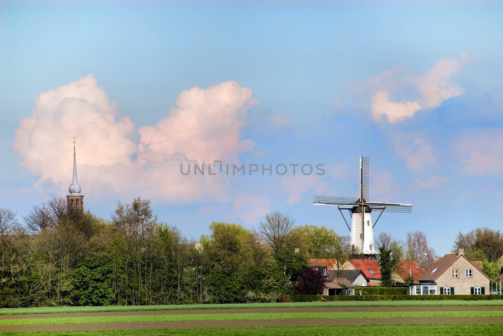 landscape sight on little village with windmill and churchtower