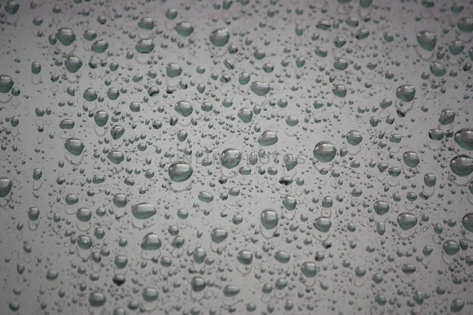 Drops of water on dark shiny glass.