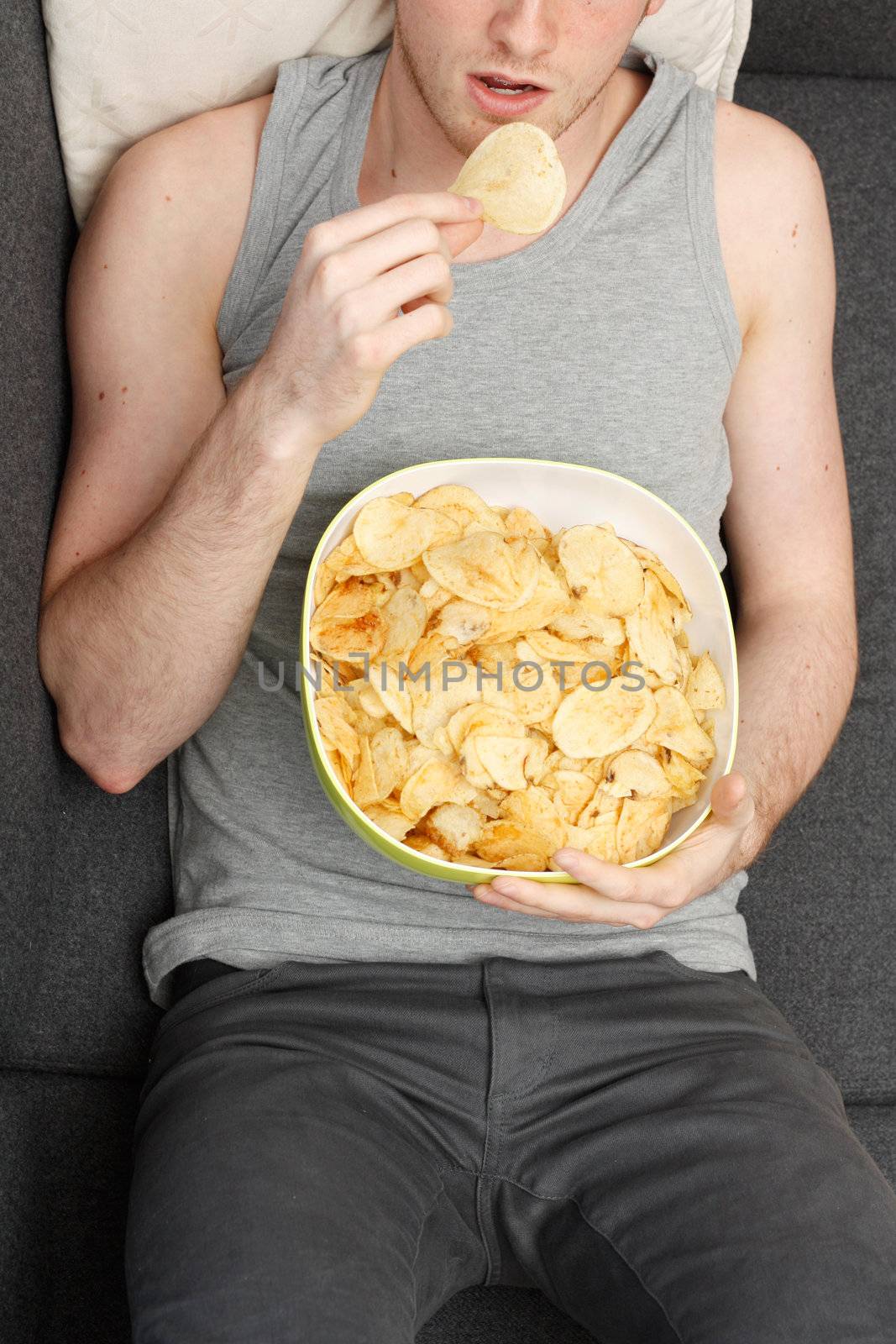 A man on a couch eating potato chips