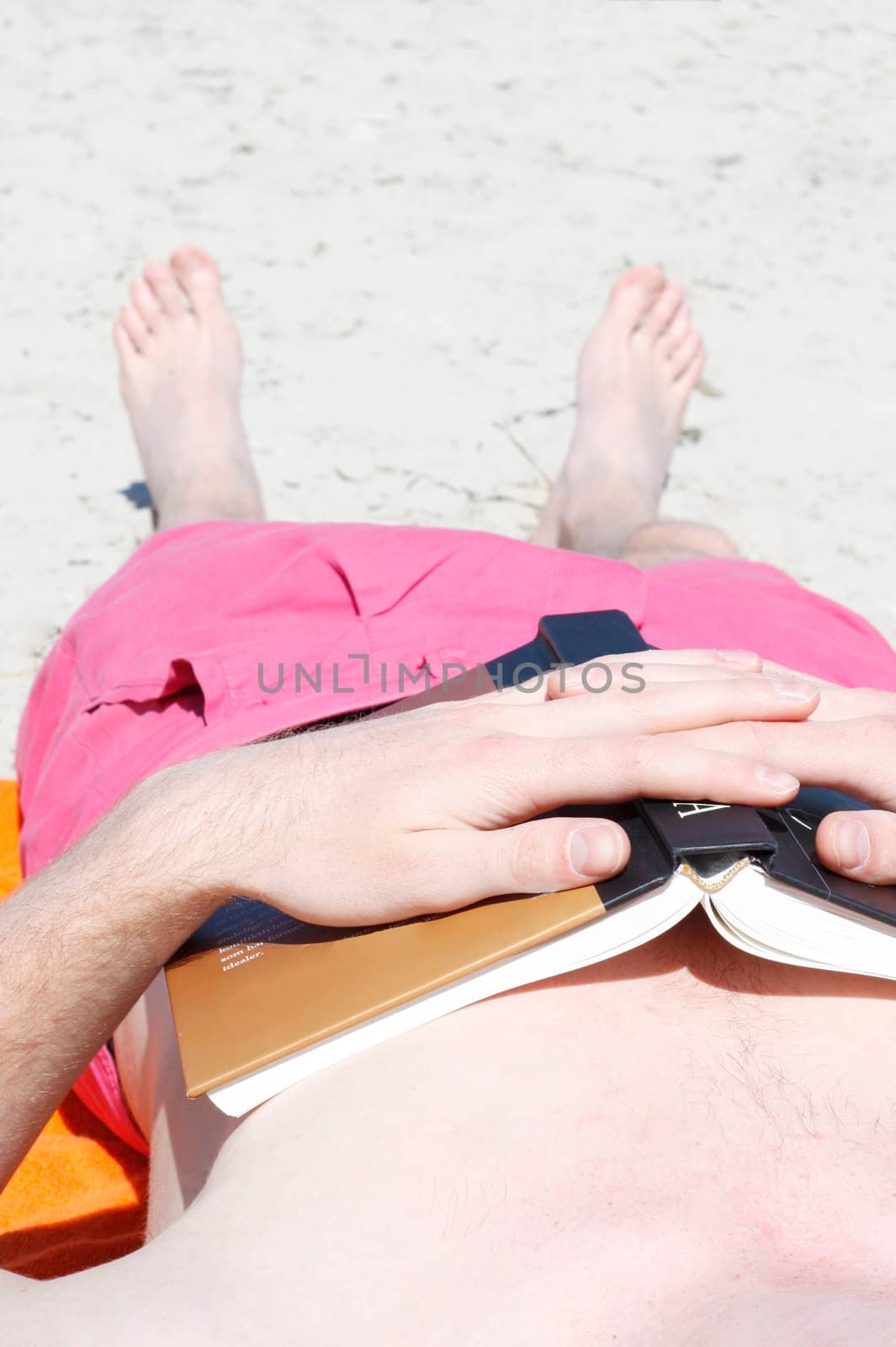Man sleeping on beach after reading a book
