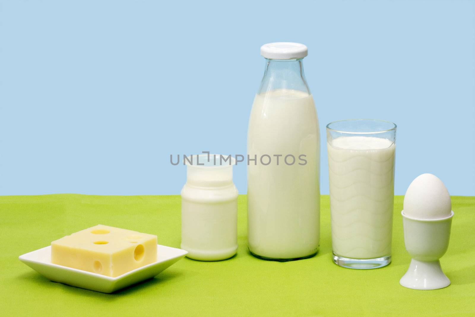 Fresh milk, yogurt, cheese and egg over blue background