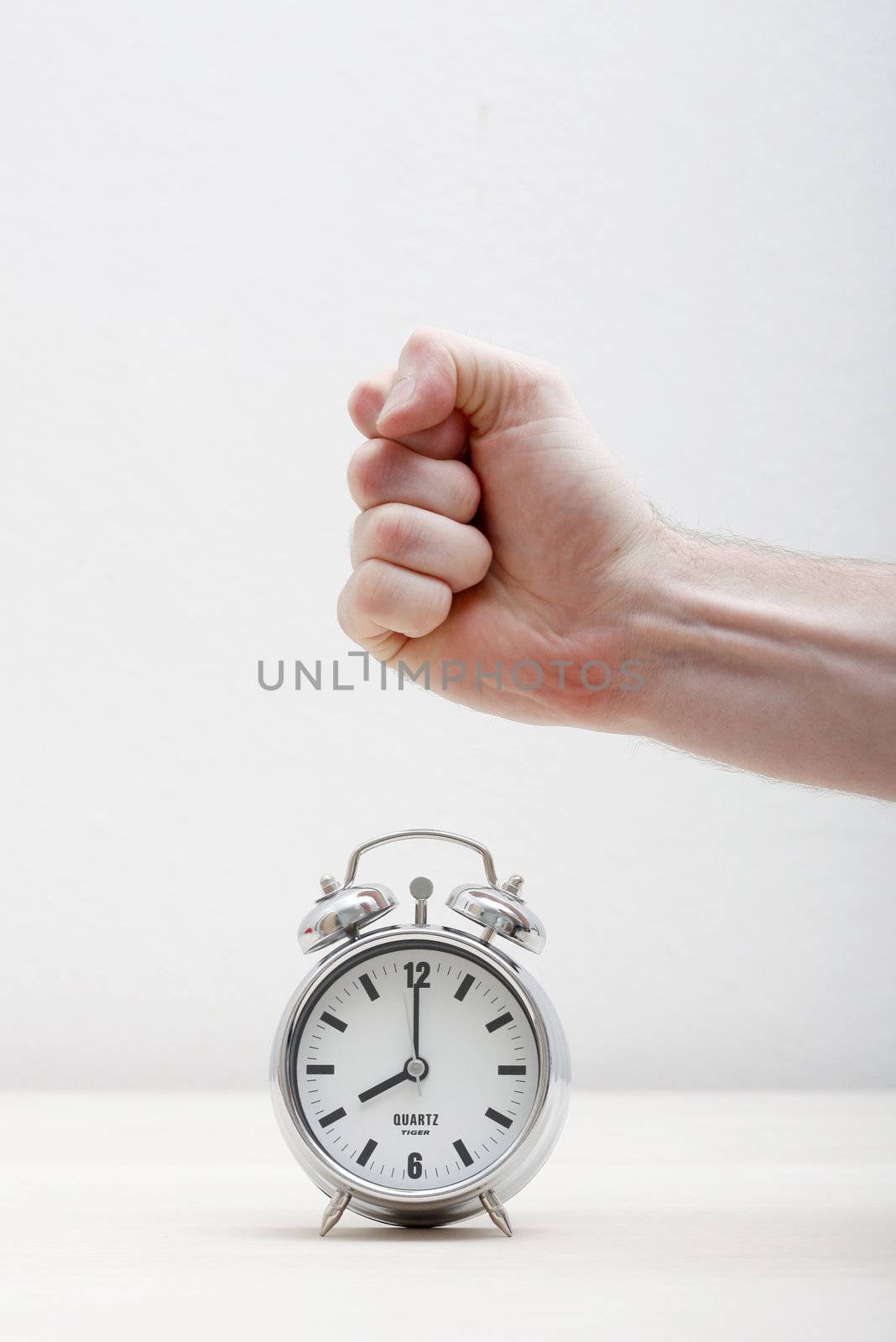 A hand breaking an alarm clock