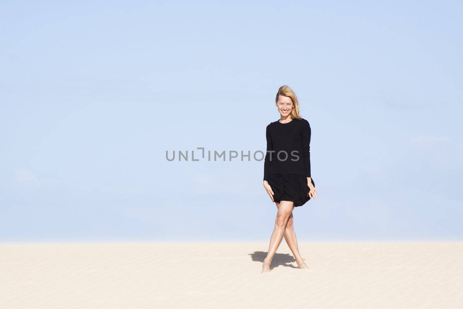 Beautifull girl in black dress posing on the sand dune.