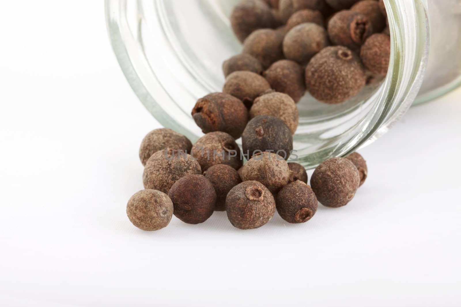 Fragrant pepper and glass cruet on white background. Macro shot