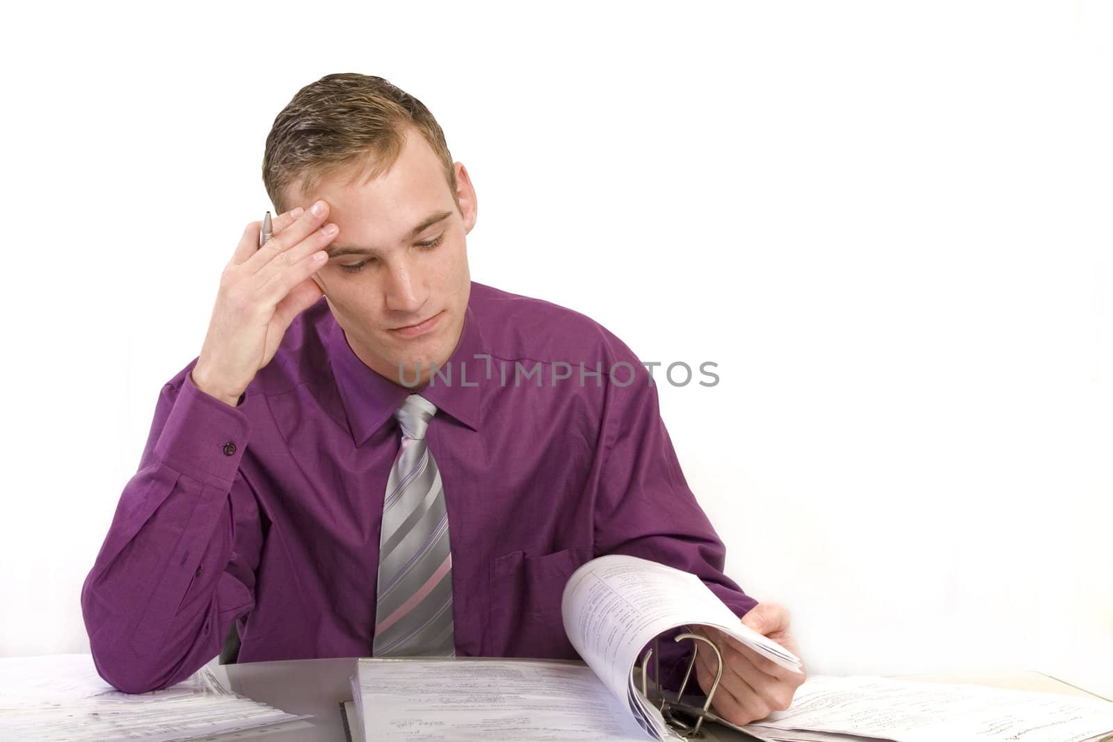 Businessman at his desk in the office thinks. He looks worried while on a file folder. 