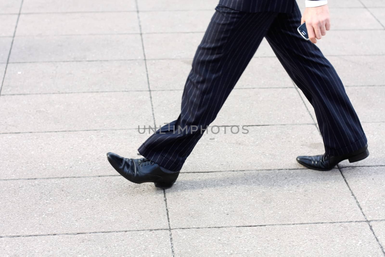 A business man walking with a phone in his hand