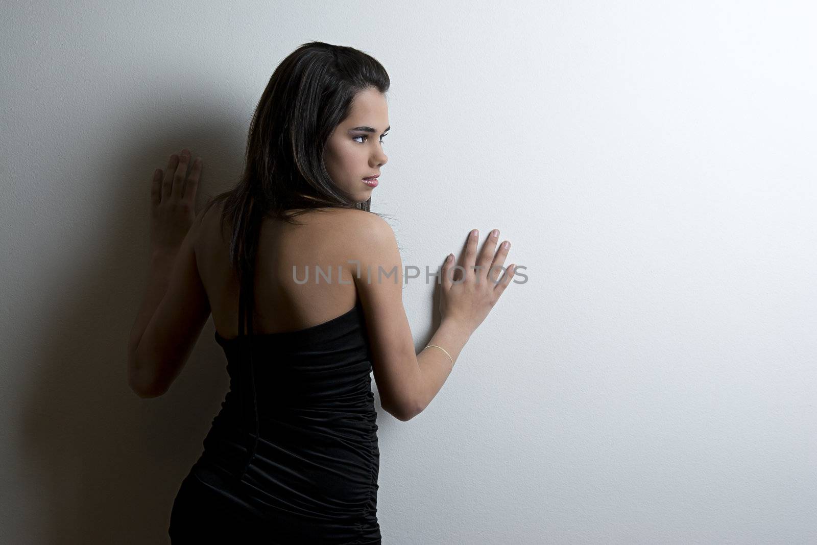 Young woman in black dress leaning against wall