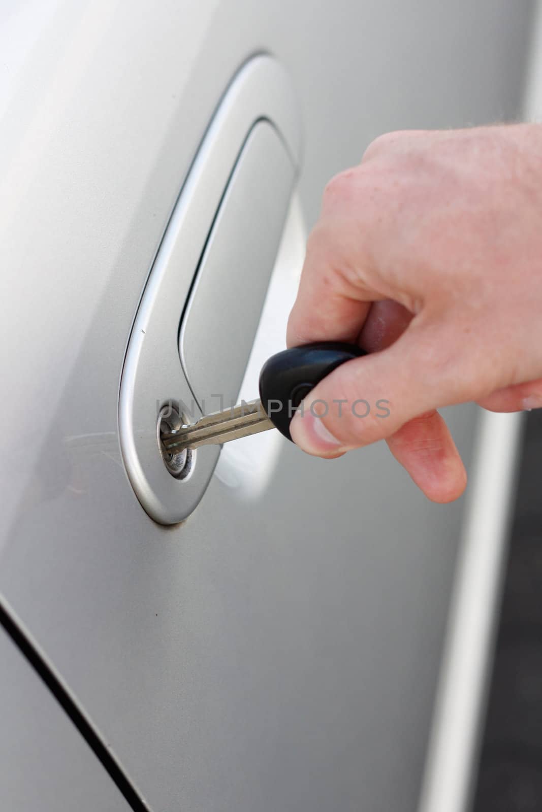 A hand opening a car door with a key