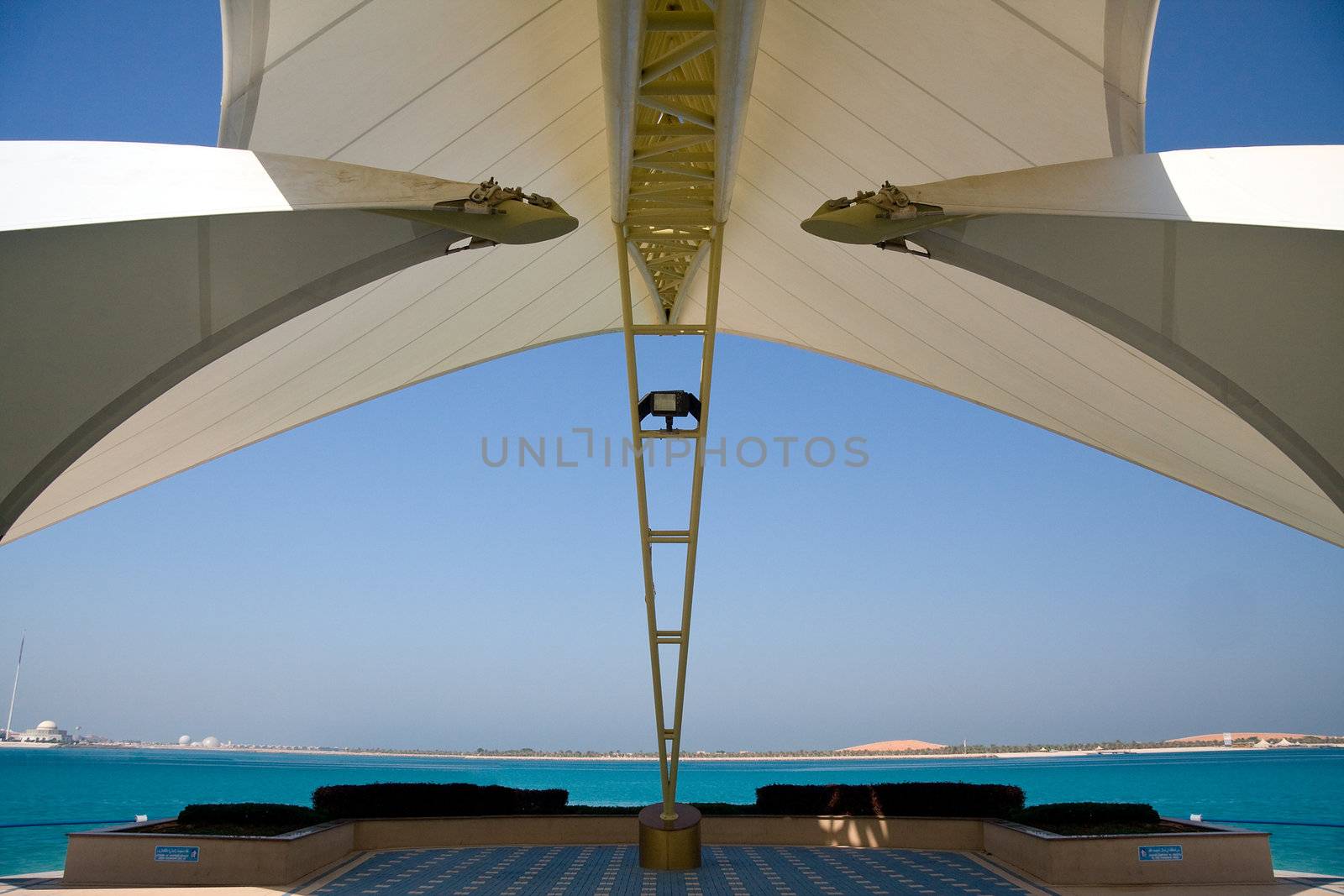 Modern sail like construction providing shade and framing a view of gulf and distant sand dunes