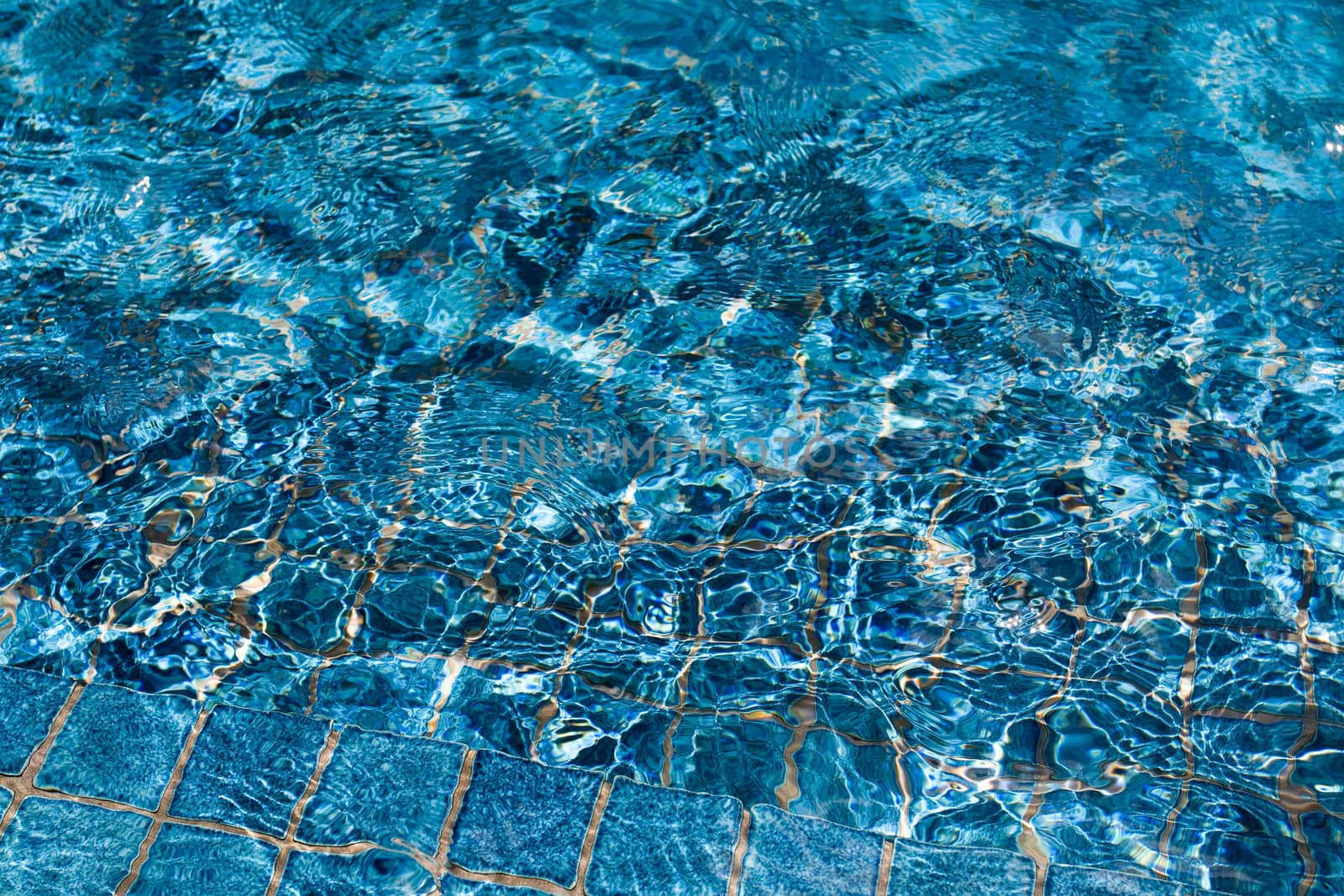 Background of deep blue swimming pool water sparkling in sunlight