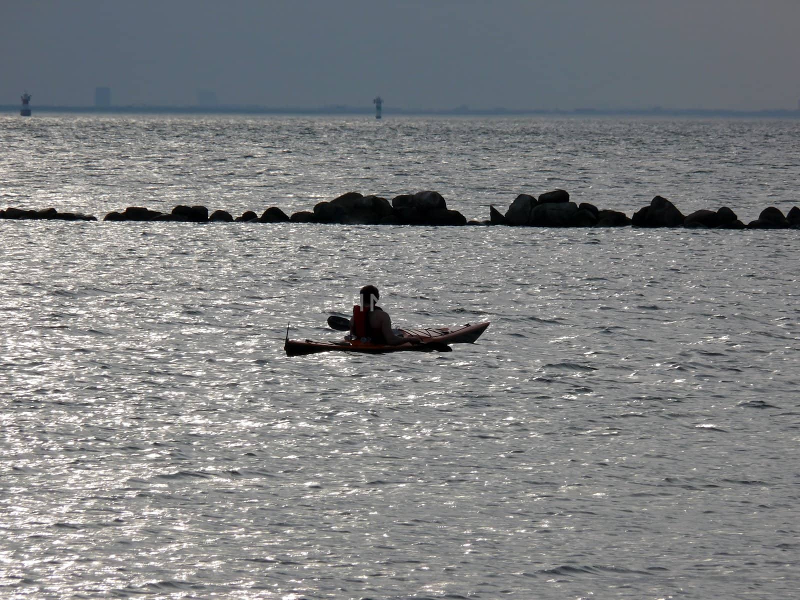 portrait of man in kayak watching ocean landscape in sunset