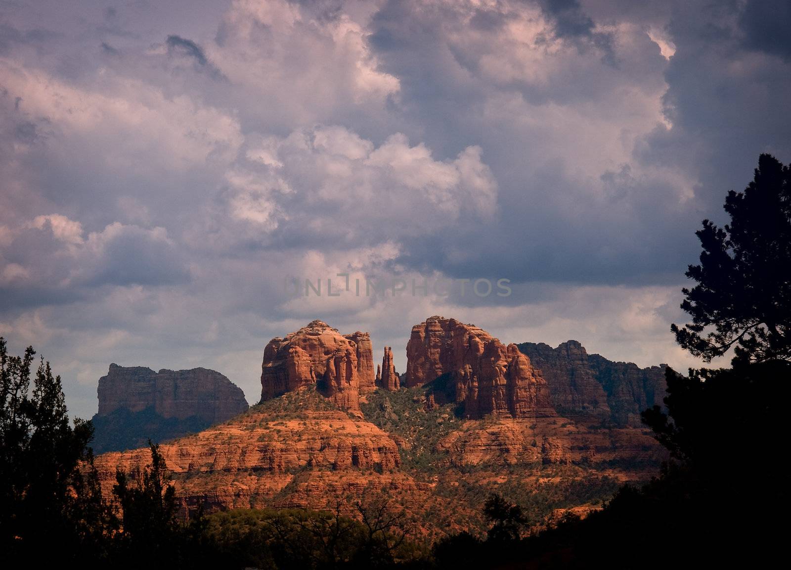Sedona rocks brilliantly lit by the sun in front of heavy storm clouds