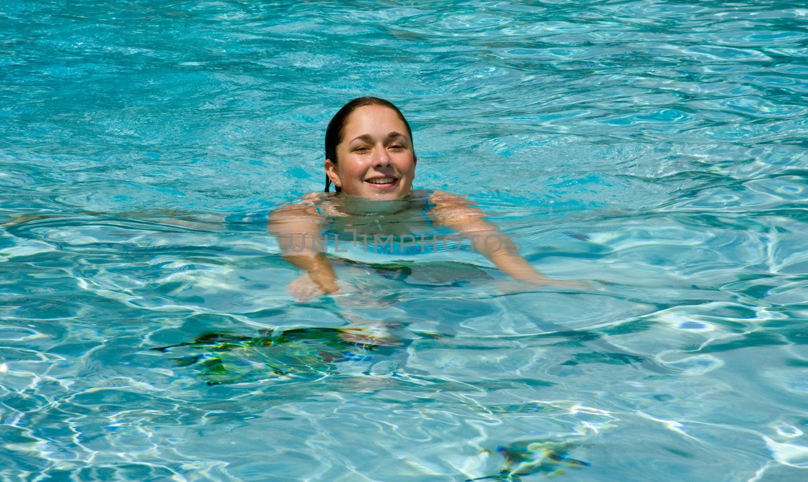 Your female teenager swimming towards the camera in blue pool