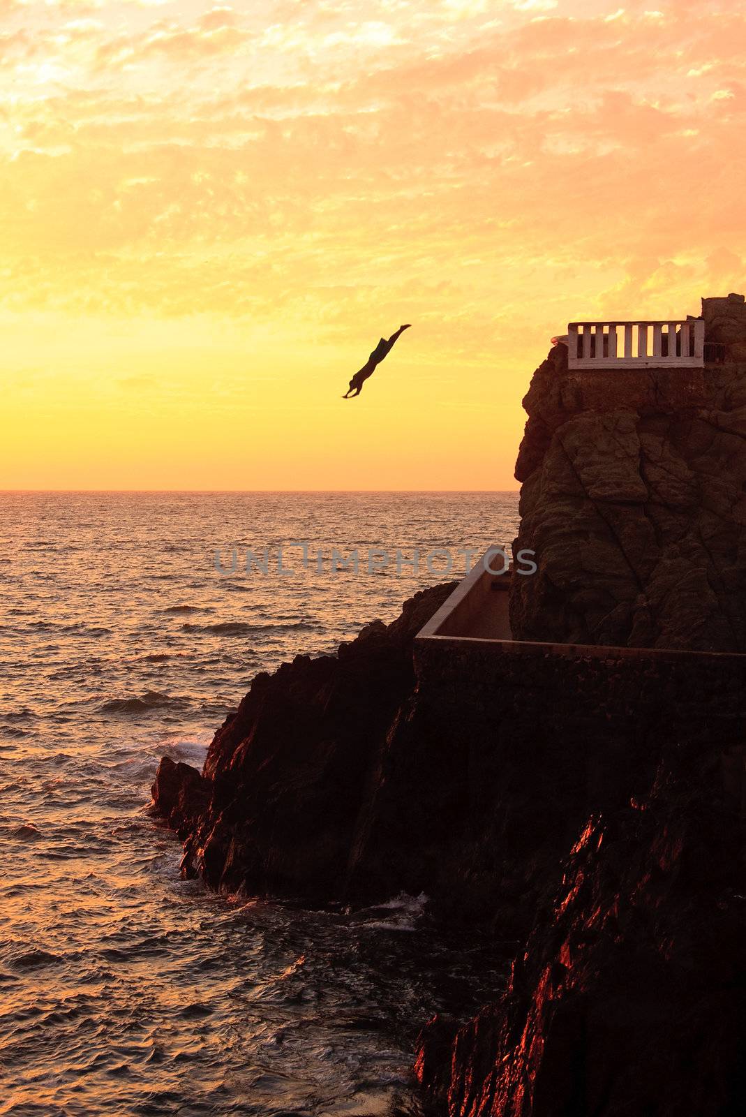 Young diver making straight dive into the sea at Mazatlan at sunset