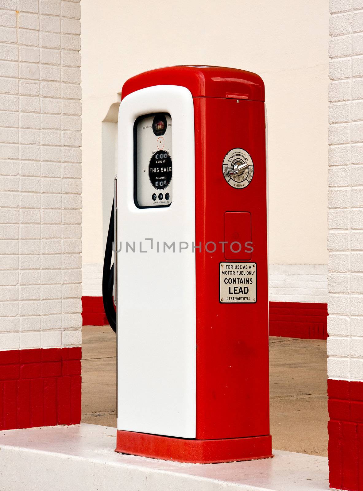 Ancient gas pump painted in bright white and red in the setting of an old gas station