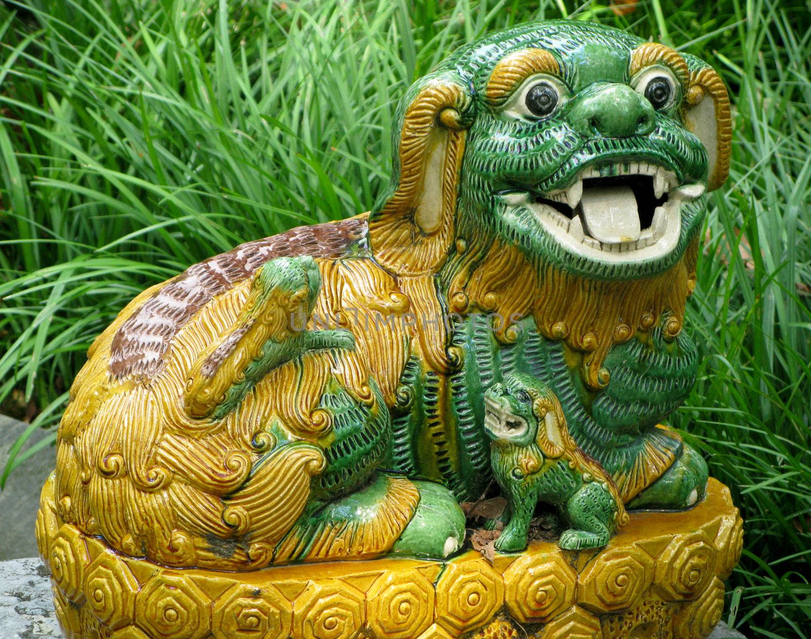 Close-up of pottery lion or dog in deep grass in garden