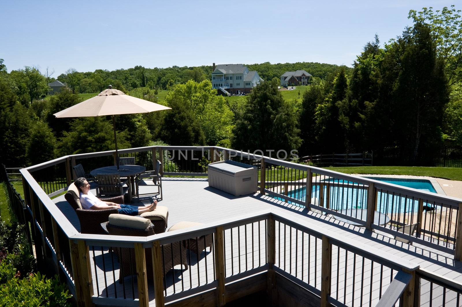 Middle aged lady relaxing on a deck by a swimming pool