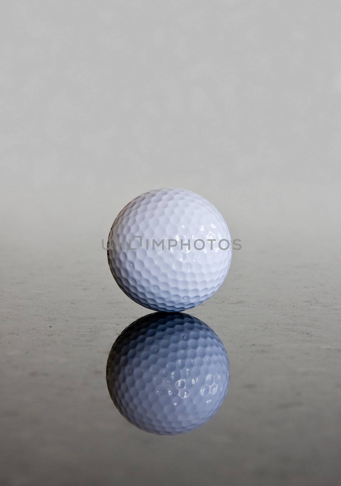 Single golf ball reflecting off a shiny marble surface